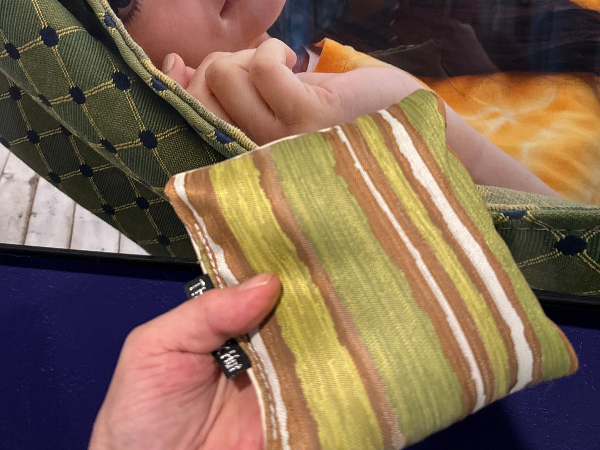 Premium Painted Stripe Green cornhole bag held in hand, landscape product photo