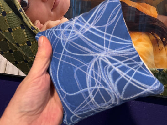 Premium Scribble Sapphire Blue cornhole bag held in hand, landscape product photo