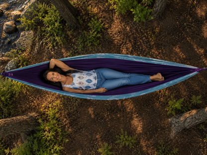 Overhead view of Kathy reclining in the Azure Solstice hammock among the pines