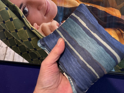 Premium Painted Stripe Blue cornhole bag held in hand, landscape product photo