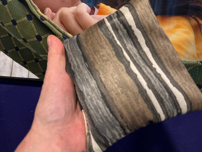 Premium Painted Stripe Brown cornhole bag held in hand, landscape product photo