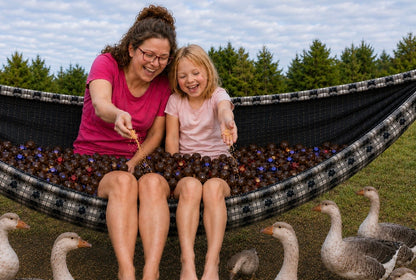 Mother and daughter sitting in Chocoholic Premium Hammock feeding geese