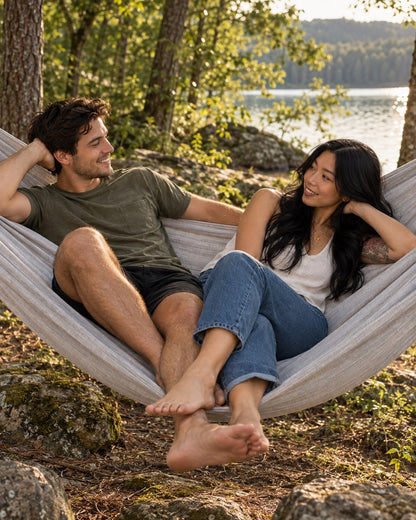 Two adults relaxing in the Concrete + Premium Hammock beside a lake