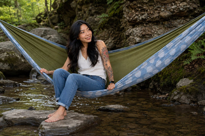 Woman sitting on the edge of Fernwater Solstice Premium Hammock by the creek