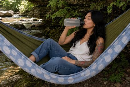 Woman relaxing with a water bottle in Fernwater Solstice Premium Hammock