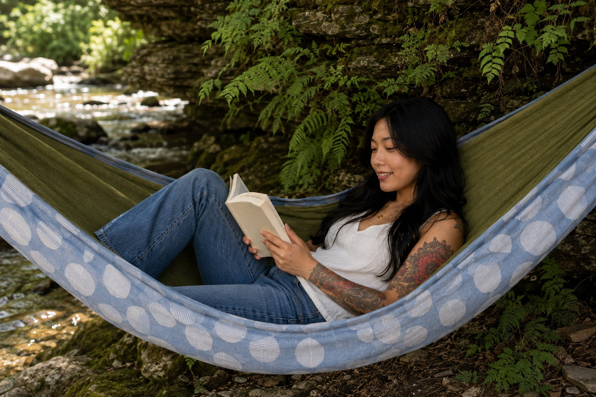 Woman reading in Fernwater Solstice Premium Hammock beside a woodland creek
