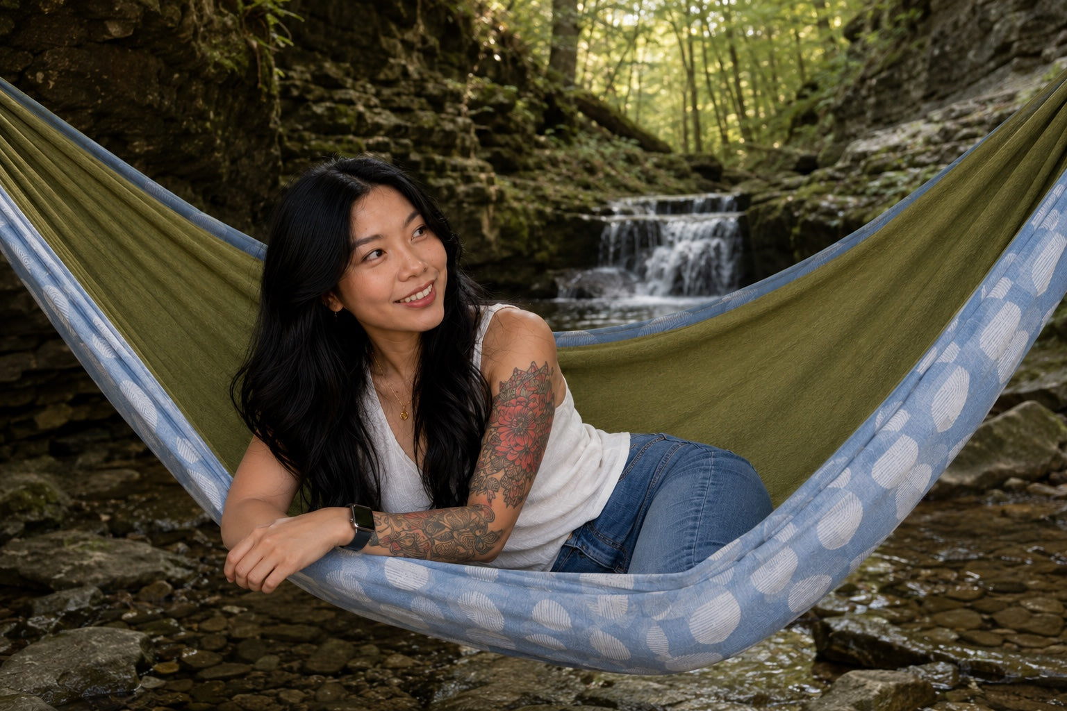Woman reclining in Fernwater Solstice Premium Hammock near a small waterfall