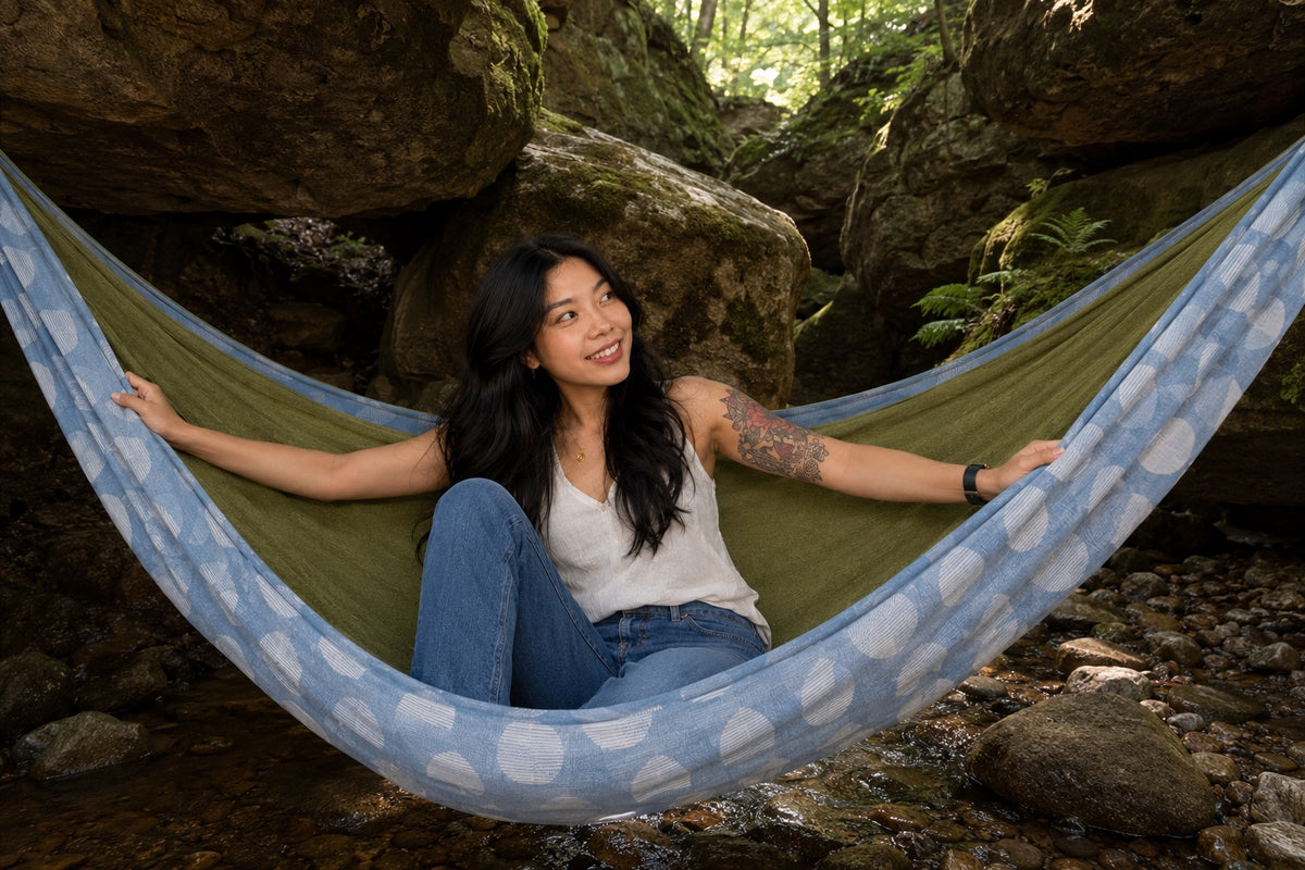 Woman stretching out in Fernwater Solstice Premium Hammock beneath a rocky grotto
