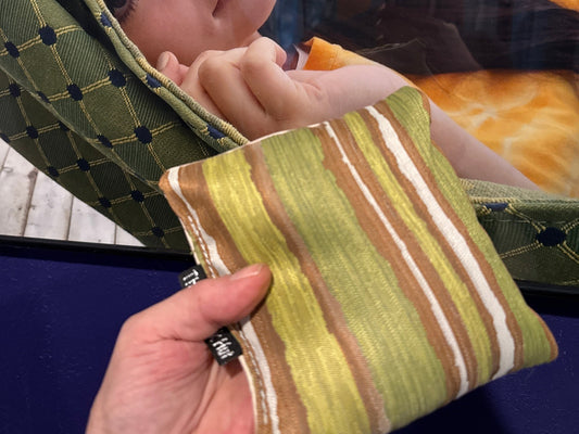Premium Painted Stripe Green cornhole bag held in hand, landscape product photo