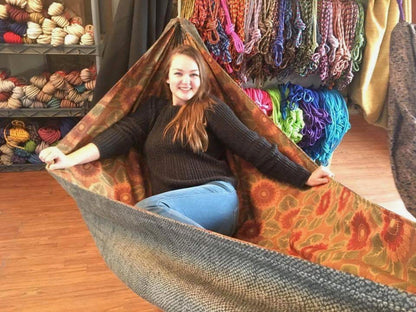 A smiling customer trying a handmade Hammock Hut hammock inside the shop.