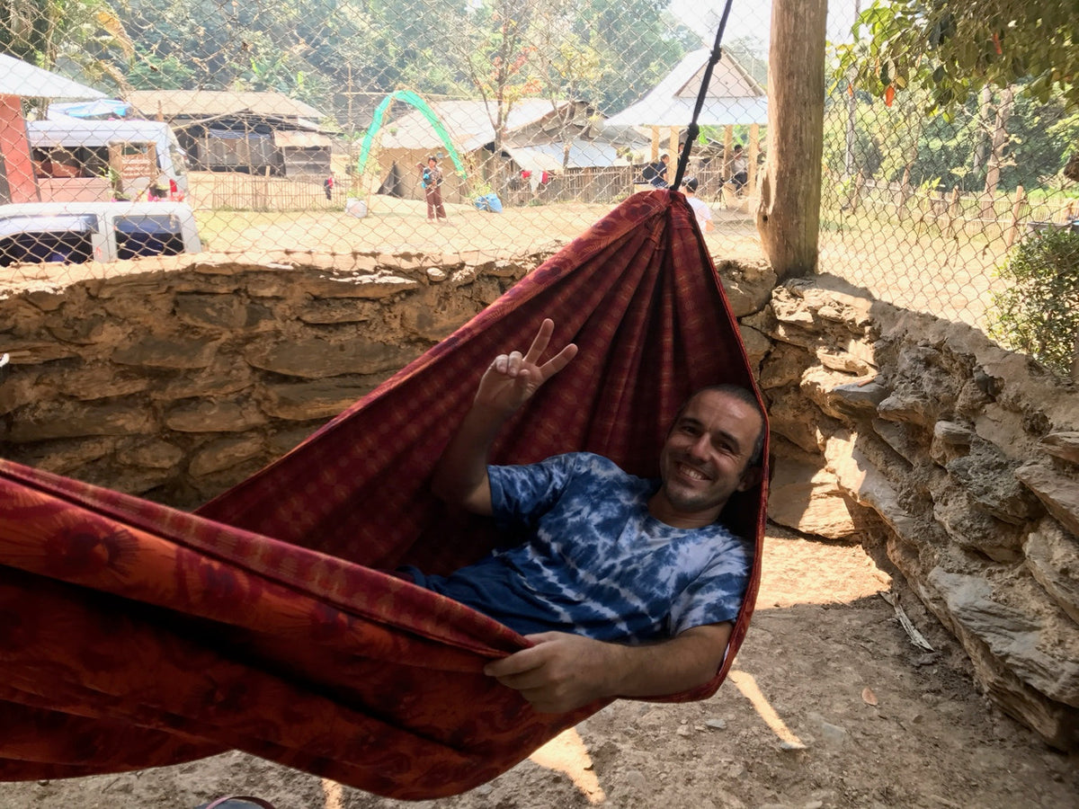 A happy traveler relaxing in a red Hammock Hut hammock.