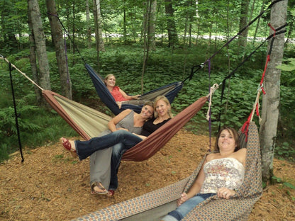 Friends enjoying several handmade Hammock Hut hammocks together in the forest.