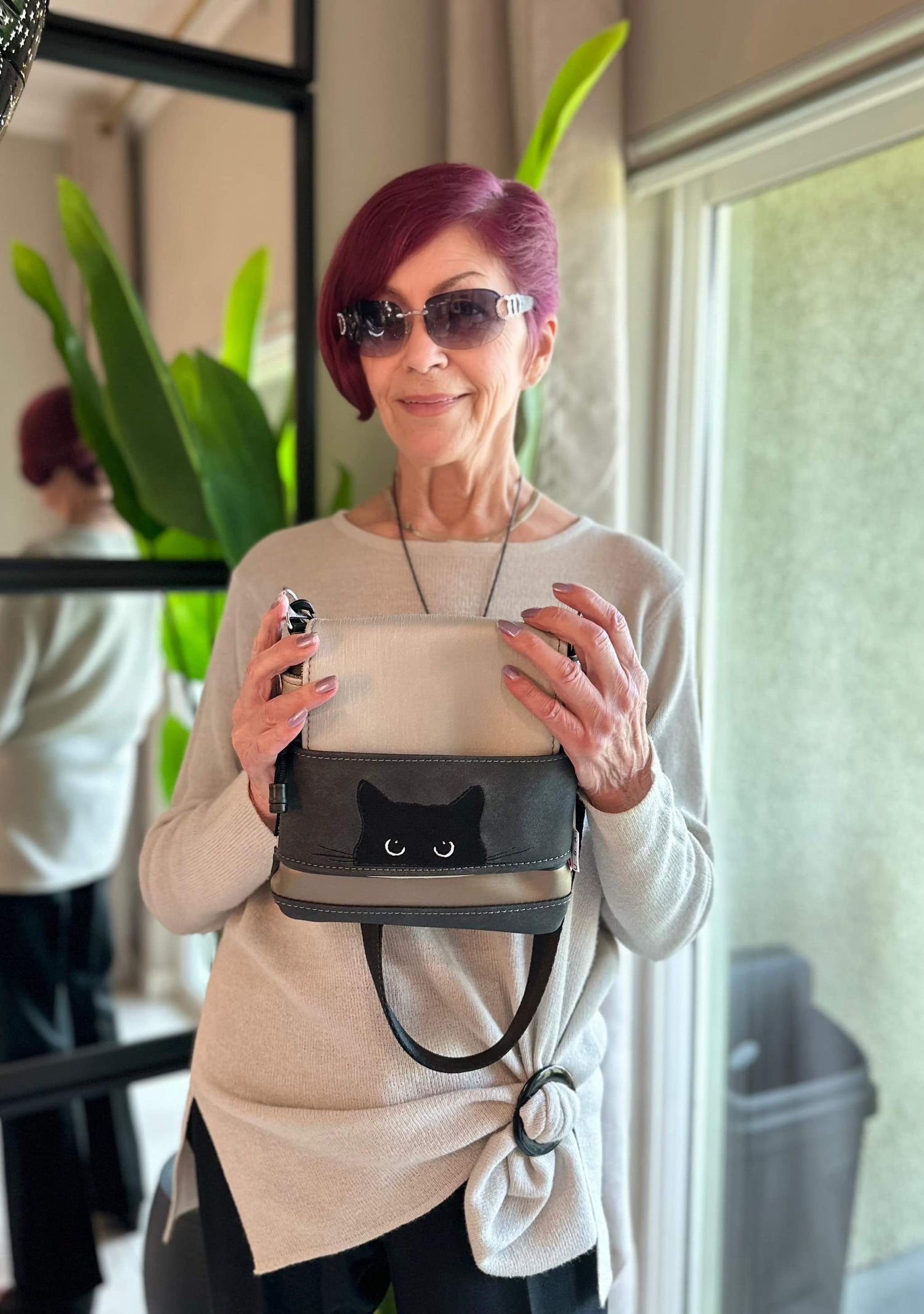 Woman holding a handmade Hammock Hut crossbody bag with a black cat design.