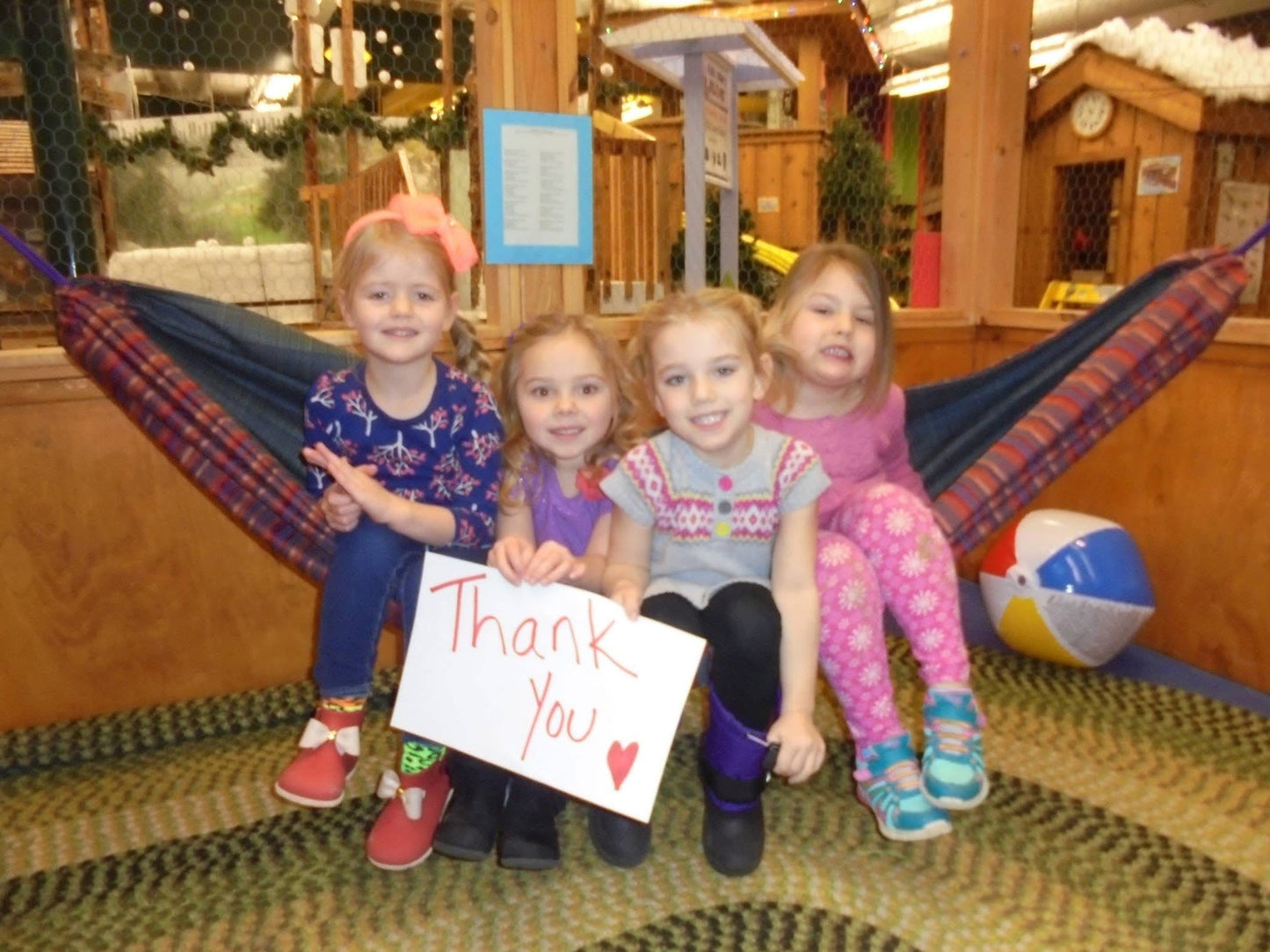 Four children together in a handmade Hammock Hut hammock with a thank-you sign.