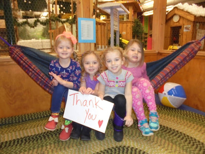 Four children together in a handmade Hammock Hut hammock with a thank-you sign.