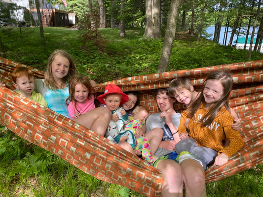 A group of children enjoying a large handmade Hammock Hut hammock by a Northwoods lake
