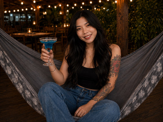 Moonstone Solstice Premium Hammock with smiling model holding a blue drink under warm string lights