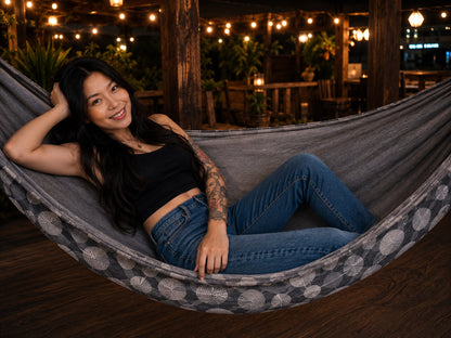 Moonstone Solstice Premium Hammock with model reclining comfortably under warm evening lights