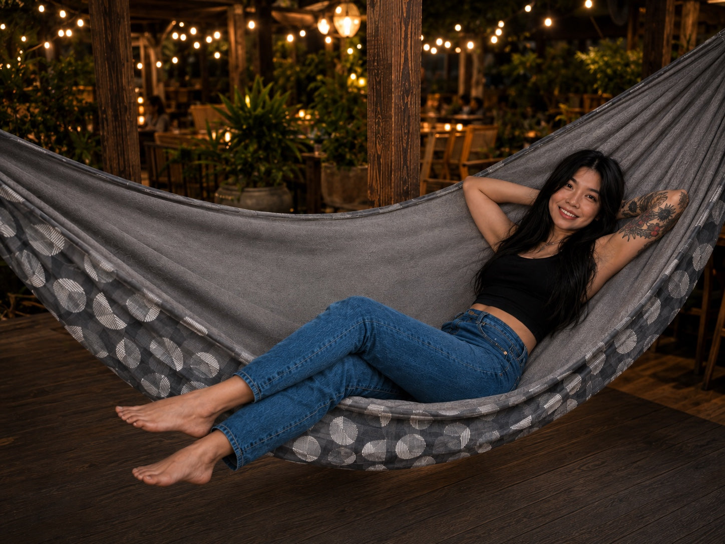 Moonstone Solstice Premium Hammock with model relaxing under warm string lights