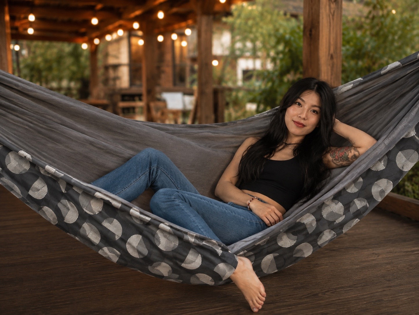 Moonstone Solstice Premium Hammock with model reclining in a warm patio setting