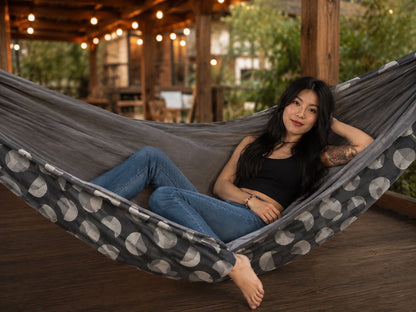 Moonstone Solstice Premium Hammock with model reclining in a warm patio setting
