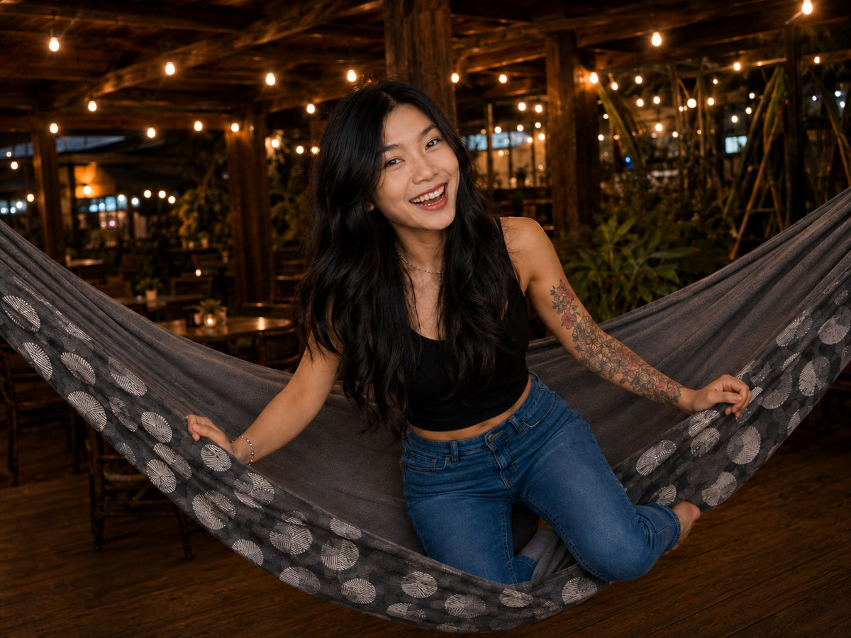 Moonstone Solstice Premium Hammock with joyful model kneeling and laughing under string lights