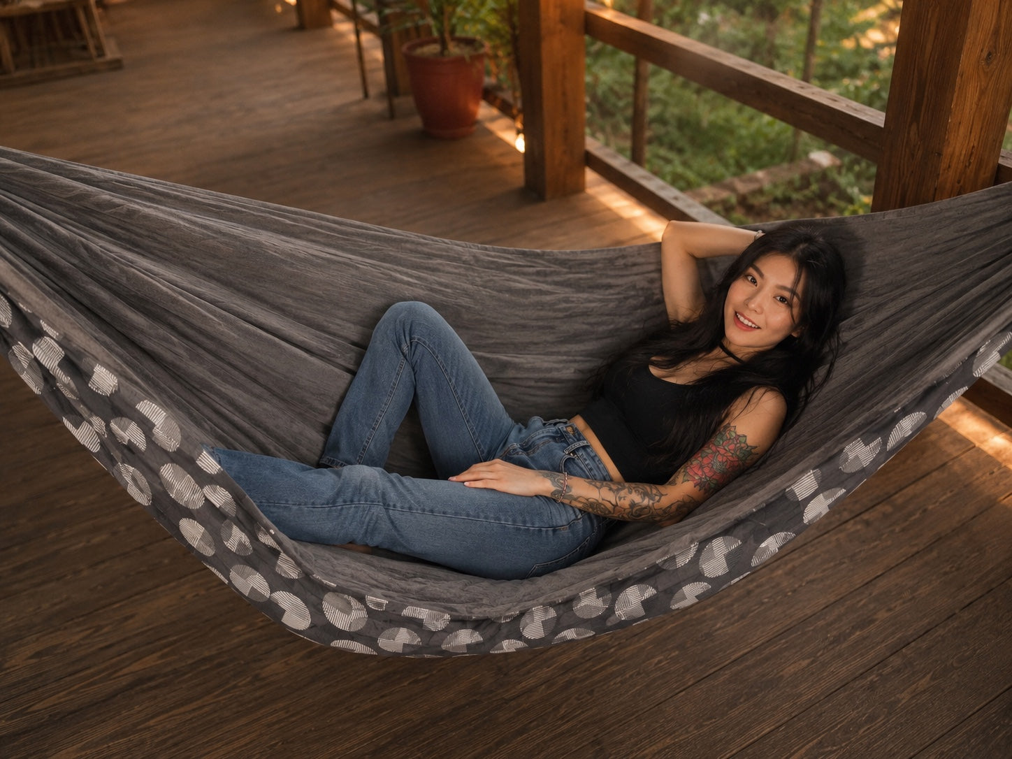 Moonstone Solstice Premium Hammock with model relaxing on a warm wooden deck