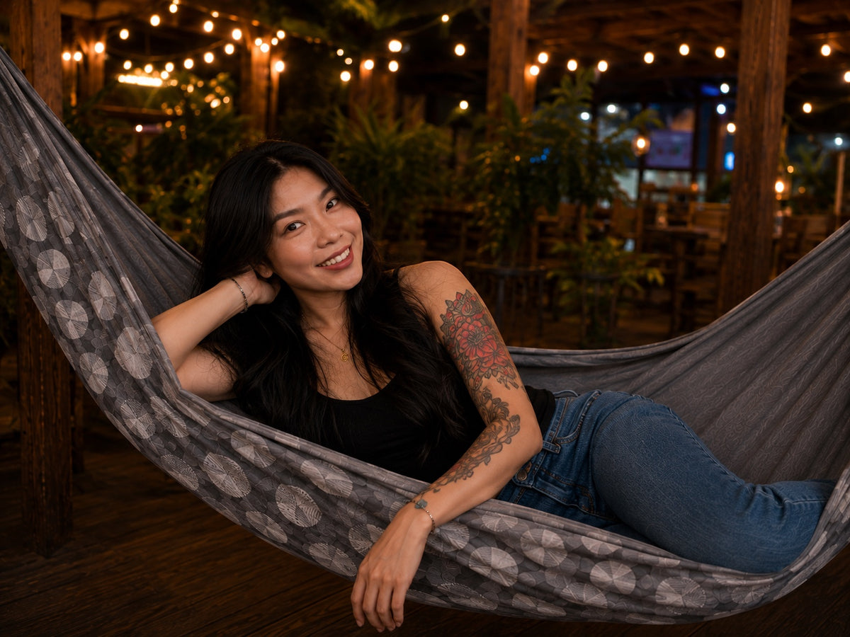 Moonstone Solstice Premium Hammock with model reclining and smiling under warm evening lights