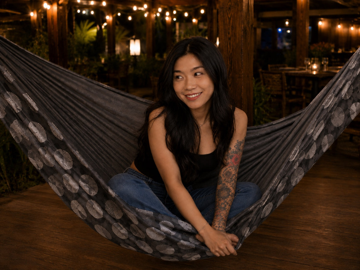 Moonstone Solstice Premium Hammock with model sitting cross-legged and looking to the side