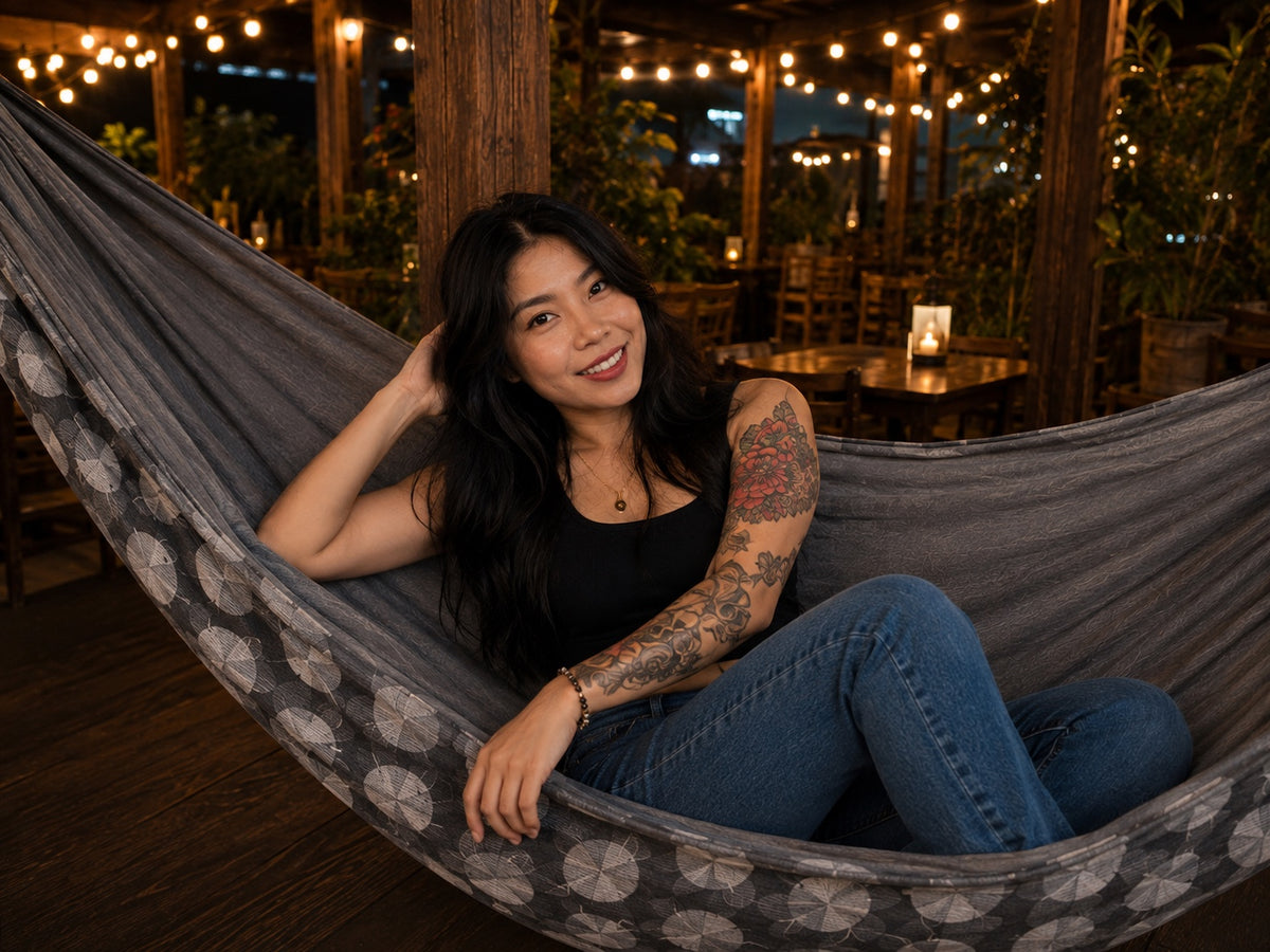 Moonstone Solstice Premium Hammock with model reclining casually beneath warm string lights