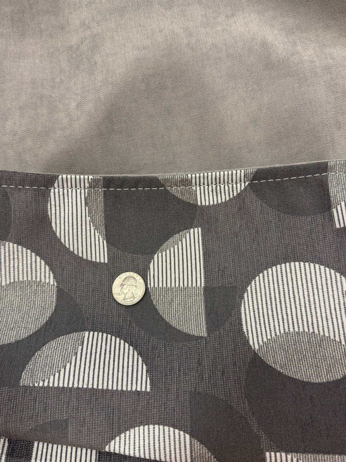Close-up of Moonstone Solstice charcoal patterned exterior and soft gray interior fabric with quarter for scale