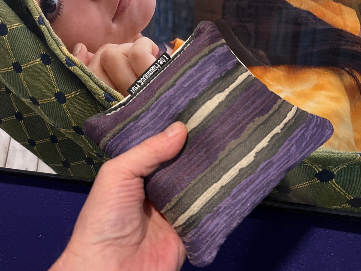 Premium Painted Stripe Purple cornhole bag held in hand, landscape product photo