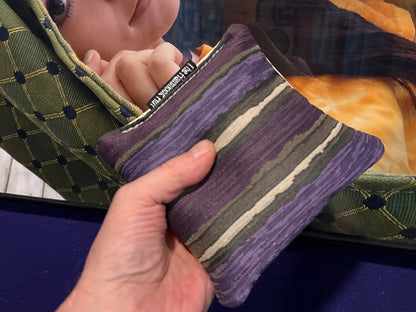 Premium Painted Stripe Purple cornhole bag held in hand, landscape product photo