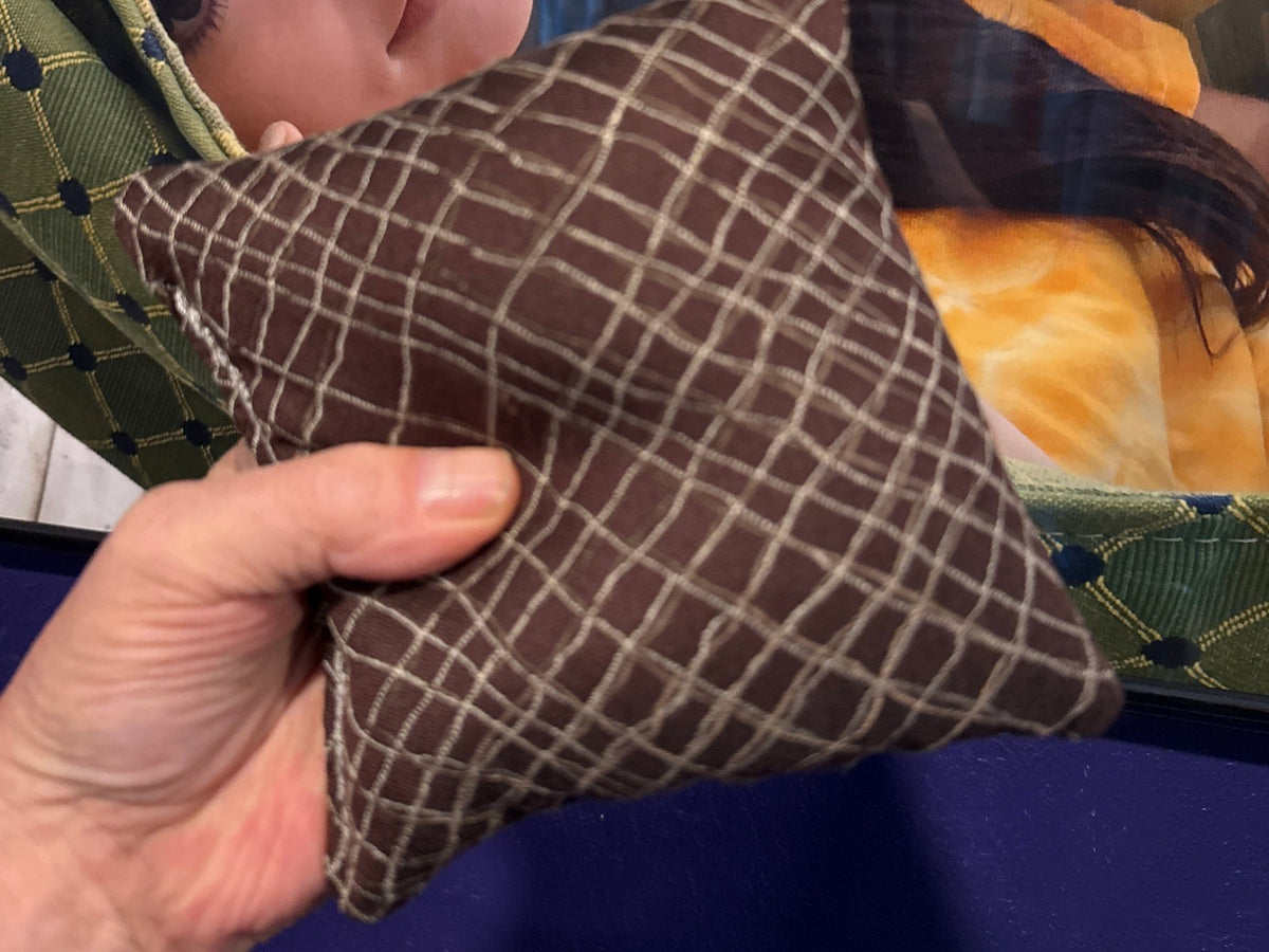 Spark Flow Mocha cornhole bag held in hand, landscape product photo