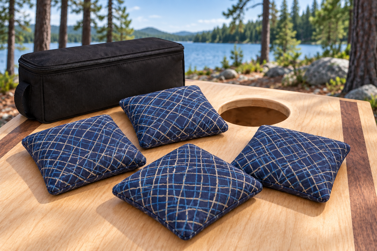 Four Spark Flow Midnight cornhole bags with matching patterned faces and black carrying case in a daytime lake setting