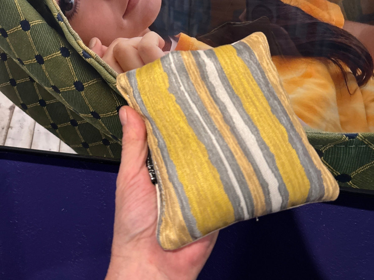Premium Painted Stripe Yellow cornhole bag held in hand, landscape product photo